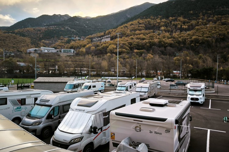 Vista del aparcamiento CanRodes con autocaravanas estacionadas y montañas al fondo.