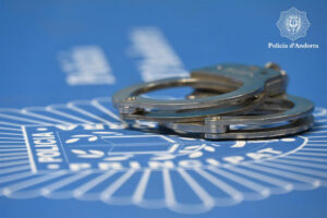 Esposas sobre un fondo con el logo de la policía de Andorra