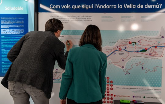 Personas interactuando con un mapa en una exposición sobre ciudades sostenibles