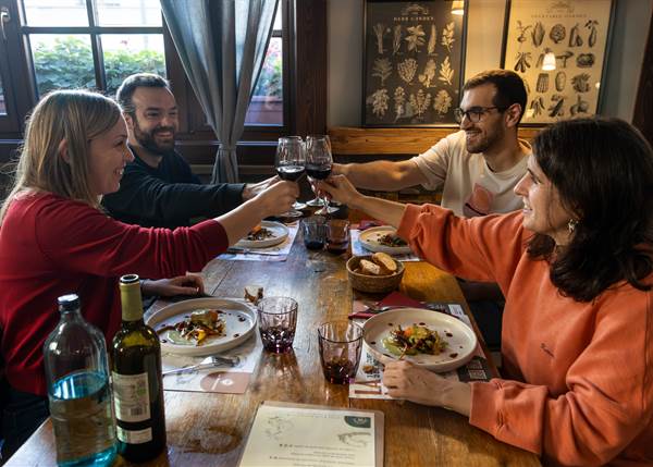 Grupo de amigos brindando con copas en una mesa con platos de comida