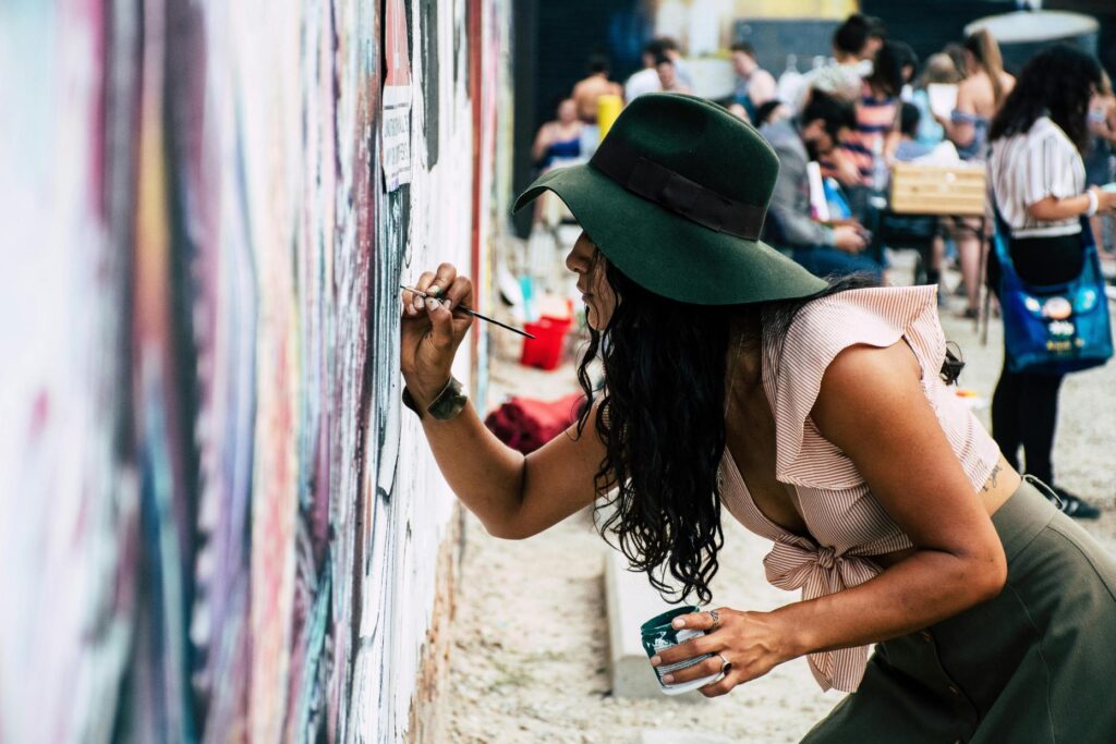 Mujer pintando un mural en un evento cultural al aire libre
