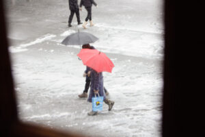 Personas caminando bajo la lluvia con paraguas en una calle