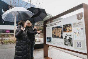 Dos personas observando un panel informativo sobre el Ball de l'Ossa en Encamp
