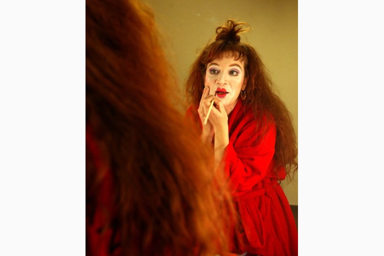Mujer con cabello rizado aplicando maquillaje en un espejo