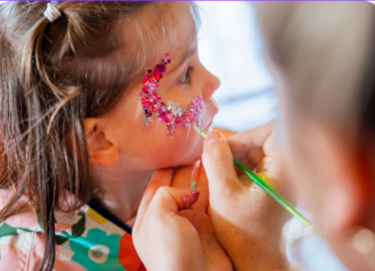 Niña recibiendo maquillaje colorido para Carnaval en un taller