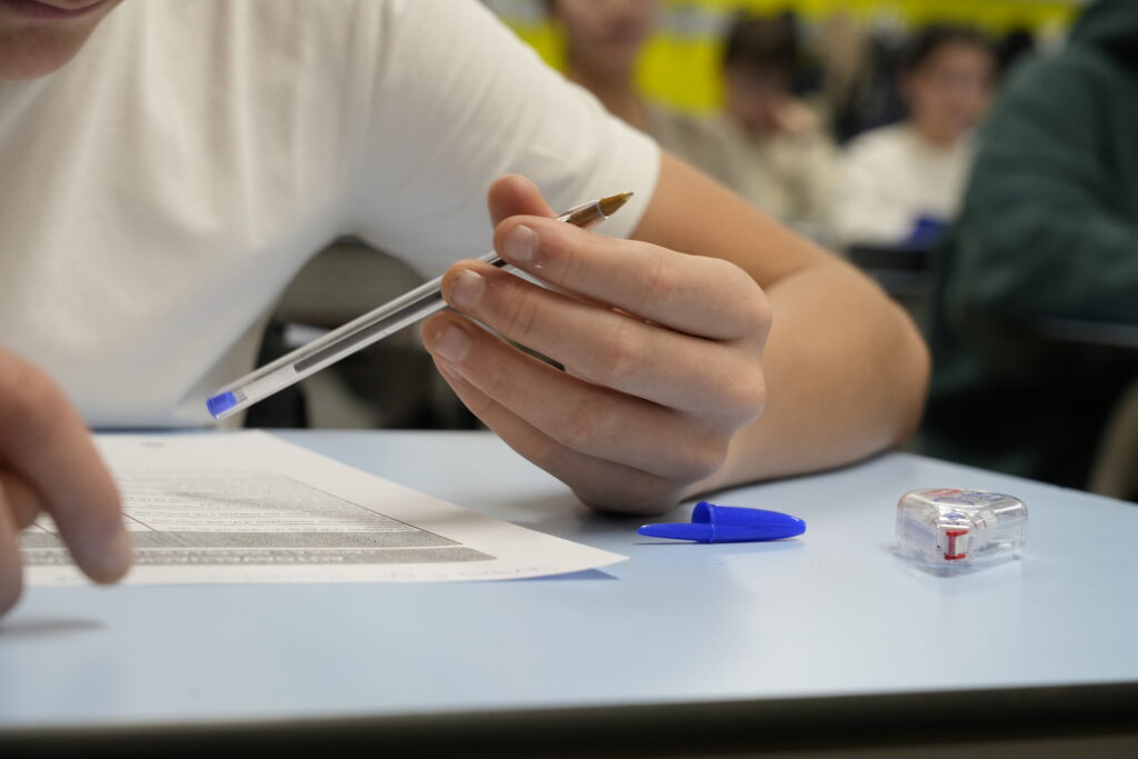 Estudiante sosteniendo un bolígrafo mientras realiza una prueba en clase