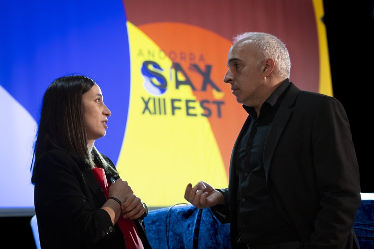 Dos personas conversando en el Andorra Sax Fest con fondo colorido