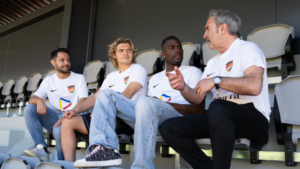 Cuatro personas conversando en un estadio con camisetas retro del Andorra