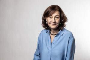 Retrato de una mujer con camisa azul, sonriendo levemente.