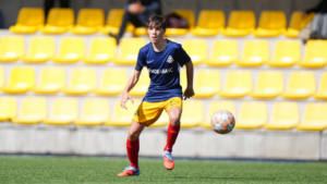Jugador del Cadete del Andorra corriendo con un balón en el campo
