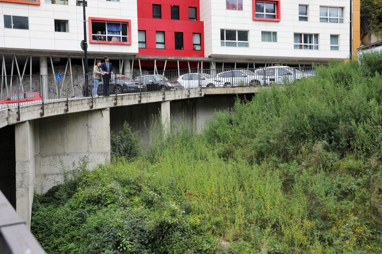 Dos personas observando un área verde junto a un edificio moderno en Terra Vella.