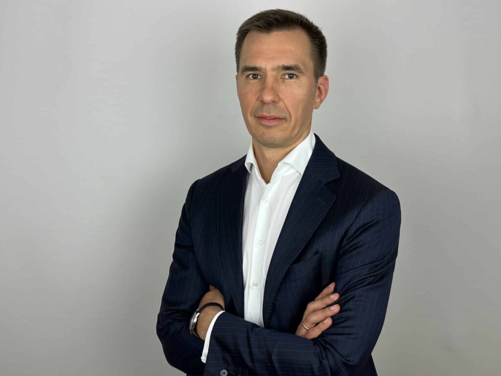 Hombre de negocios con traje oscuro y camisa blanca, posando con los brazos cruzados