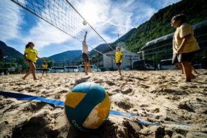 Niños jugando voleibol en la playa durante actividades deportivas