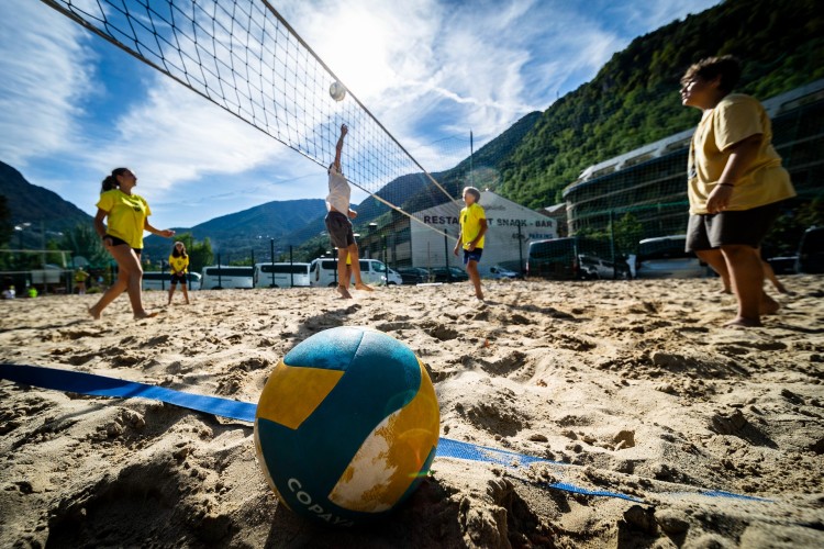 Niños jugando voleibol en la playa durante actividades deportivas