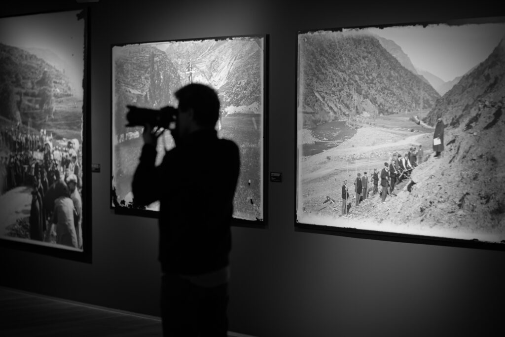 Persona fotografiando una exposición de fotografías históricas en Andorra