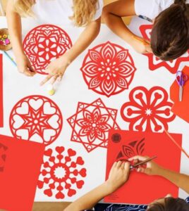 Niños participando en un taller de decoración con papel cortado rojo