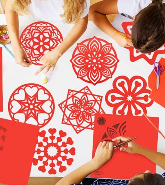 Niños participando en un taller de decoración con papel cortado rojo