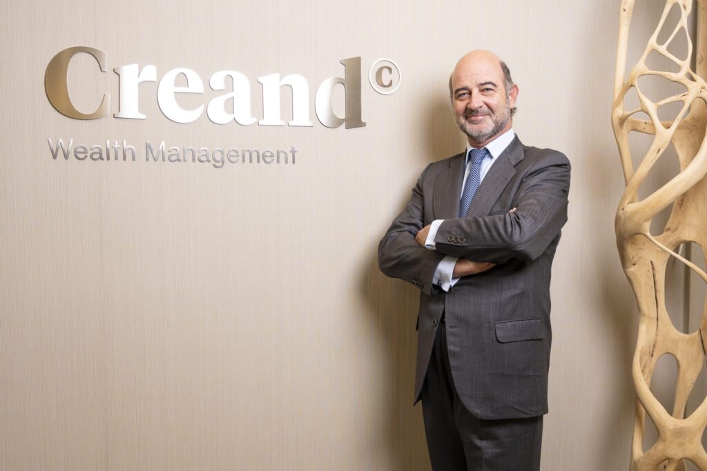 Ejecutivo de banca privada en oficina moderna con logo de Creand Wealth Management