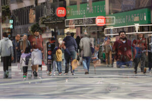 Personas caminando en una calle comercial con tiendas visibles.