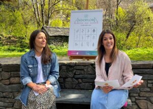 Dos mujeres presentando el evento Andoflora en un entorno natural.
