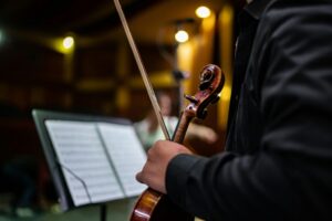 Músico sosteniendo un violín durante un ensayo de orquesta