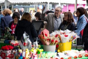 Personas en la Fira de Sant Jordi con paradas de libros y flores