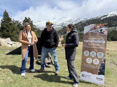 Tres personas conversando en un paisaje montañoso con un cartel de aventura de supervivencia.
