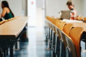 Aula con mesas y sillas vacías, enfocando en el ambiente educativo.