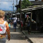 Persona con mochila de la Cruz Roja caminando por una calle