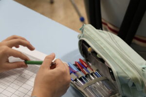 Manos de un estudiante sosteniendo un bolígrafo sobre un examen de inglés