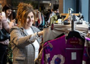 Mujer sonriendo mientras revisa ropa en el Vide Dressing de la Massana