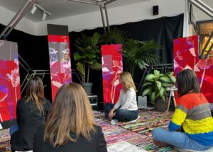 Personas sentadas en un espacio sensorial con plantas y pantallas interactivas.