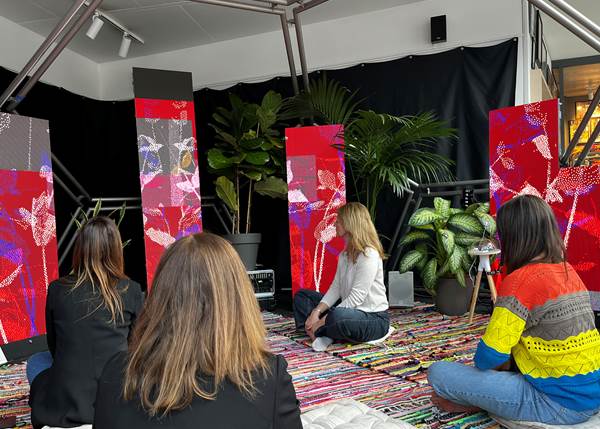Personas sentadas en un espacio sensorial con plantas y pantallas interactivas.