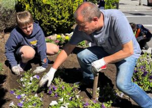 Estudiantes y padrinos plantando flores en un jardín en La Massana