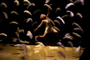 Actriz bailando entre plumas en el escenario del teatro.