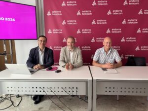 Tres personas sentadas en una mesa con el logo de Andorra Telecom de fondo