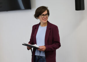 Persona sonriente sosteniendo documentos en un evento sobre archivos y patrimonio.