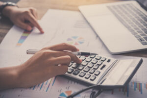 Persona usando calculadora sobre documentos de auditoría y gráficos