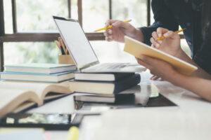 Estudiantes trabajando en un escritorio con libros y computadora