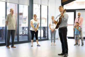 Músico tocando guitarra frente a un grupo de personas en Ordino