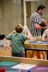 Niño participando en la World Robot Olympiad en Andorra, con mesas de competición.