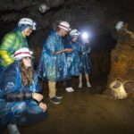 Grupo de personas explorando la Mina de Ferro de Llorts con cascos y ponchos