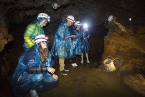 Grupo de personas explorando la Mina de Ferro de Llorts con cascos y ponchos