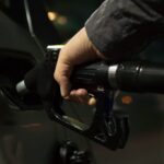 Persona llenando un tanque de gasolina en una estación de servicio