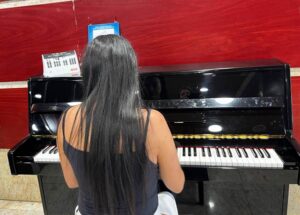 Persona tocando un piano negro en un espacio público