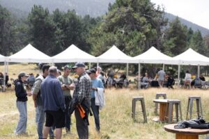 Personas conversando en un evento al aire libre con carpas blancas