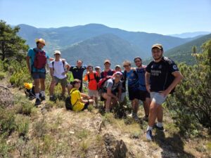 Grupo de universitarios en una caminata hacia Andorra, rodeados de montañas.
