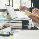 Estudiantes trabajando juntos en un proyecto académico con laptop y libros
