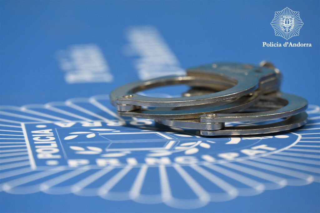 Esposas de policía sobre fondo azul con el logo de la Policía de Andorra
