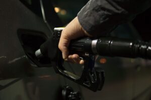 Persona llenando un tanque de gasolina en una estación de servicio